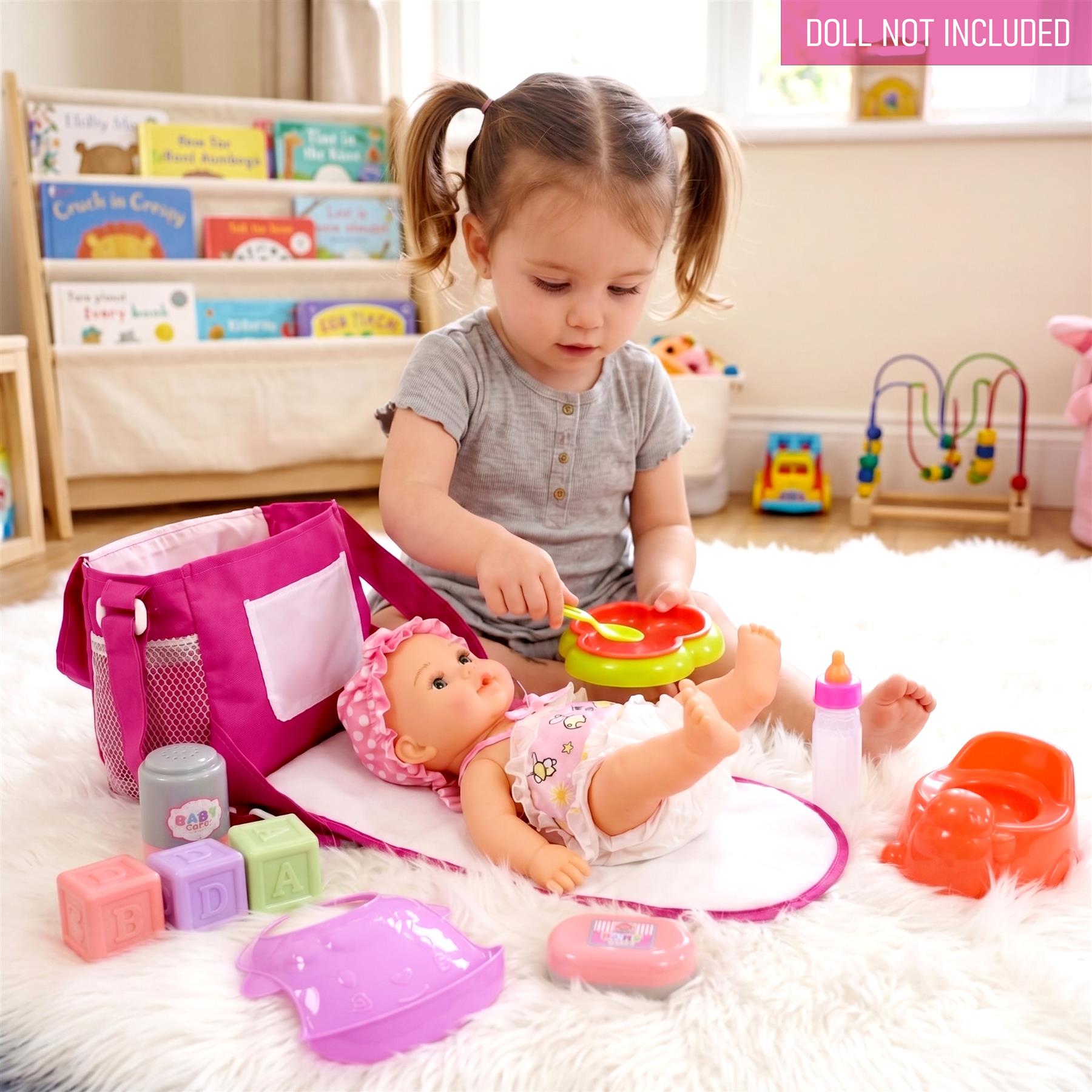A girl plays with a doll, changing bag, diapers, and various baby play accessories on a white rug.