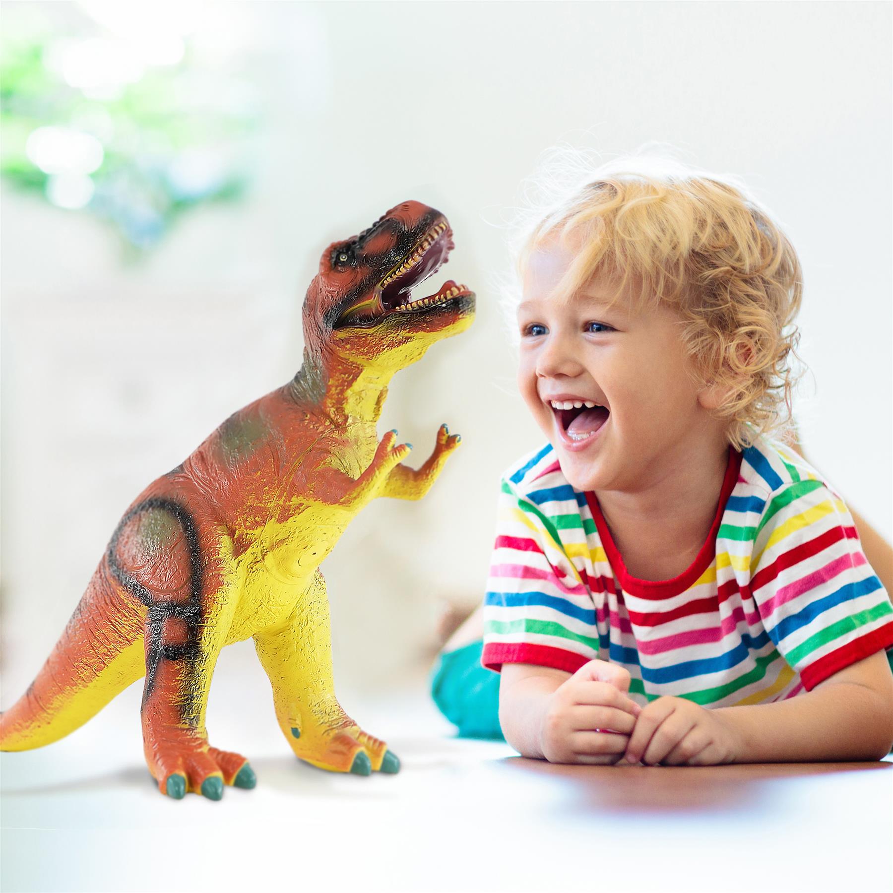 Young child smiles next to a soft foam T-Rex toy with orange and yellow colors.