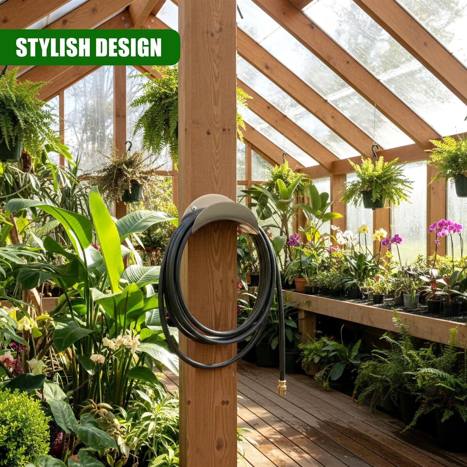 A coiled black metal hose holder is mounted to a vertical wooden post in a lush greenhouse garden.