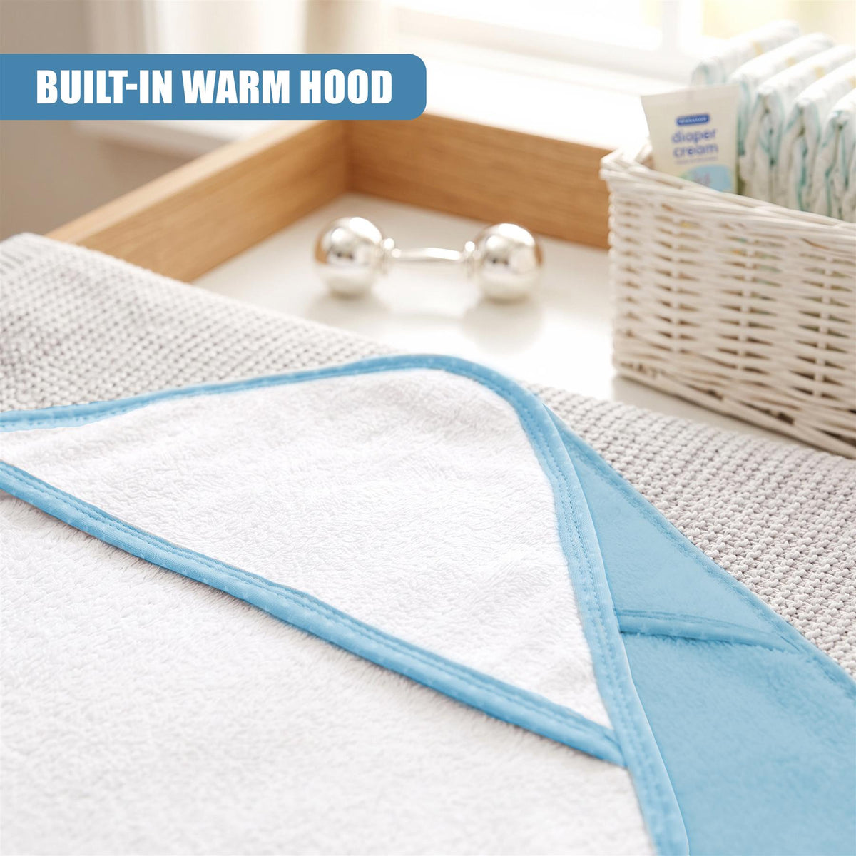 A GEEZY hooded baby bath towel set, featuring a built-in warm hood, sits on a white shelf with baby essentials