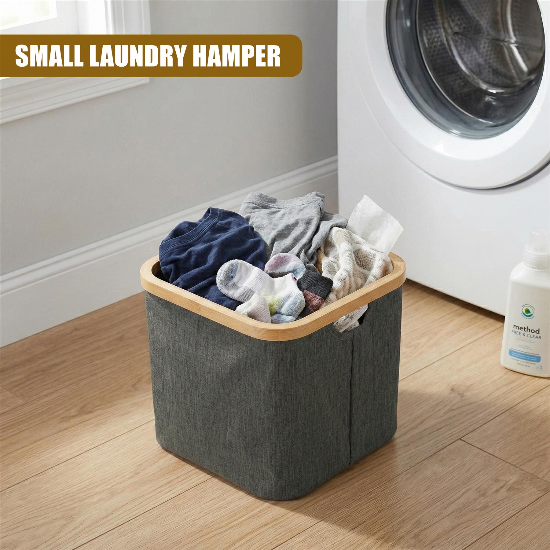 Gray, collapsible fabric laundry hamper filled with clothes sits on a wood floor by a washing machine.