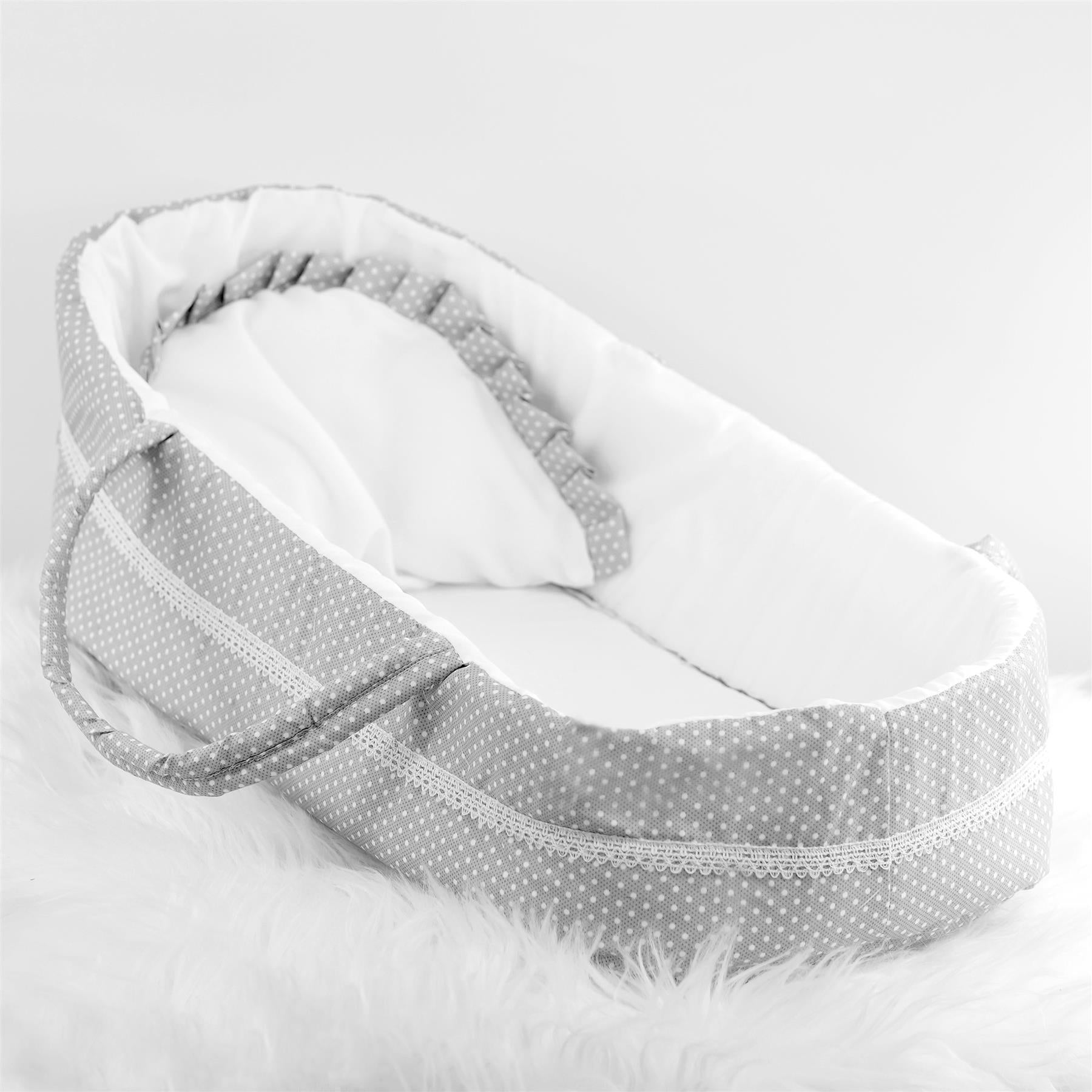 A baby's bassinet with a grey and white polka dot pattern, surrounded by a soft white fur-like material. - The Magic Toy Shop