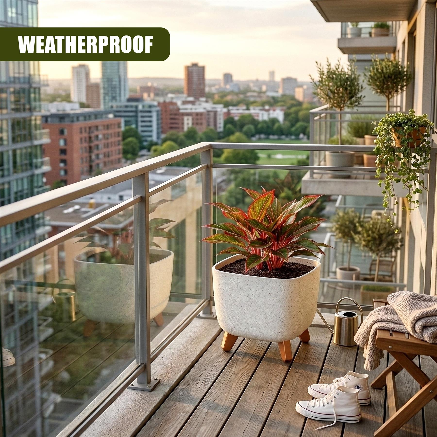 Cream flower pot with legs holds a tropical plant on a wooden balcony overlooking the cityscape.