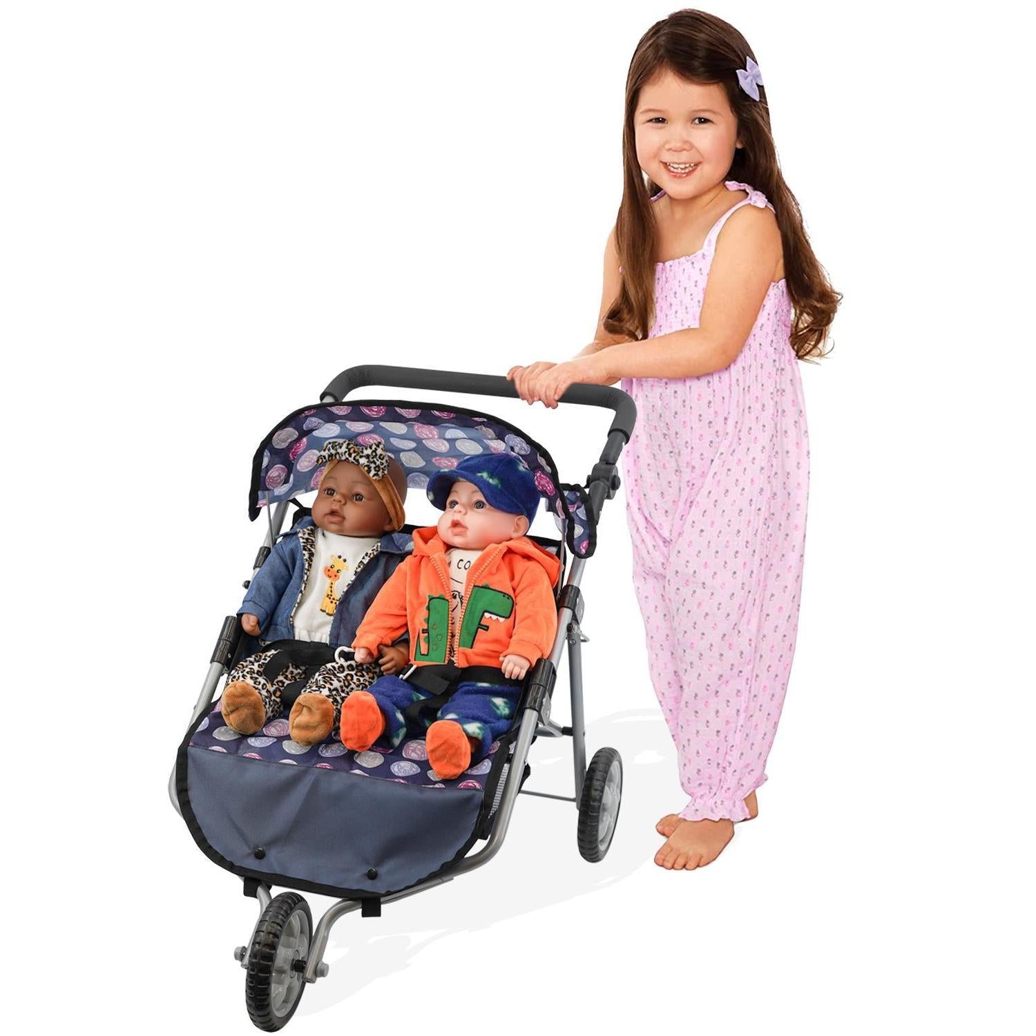 Young girl standing next to blue stroller holding two seated doll figures.