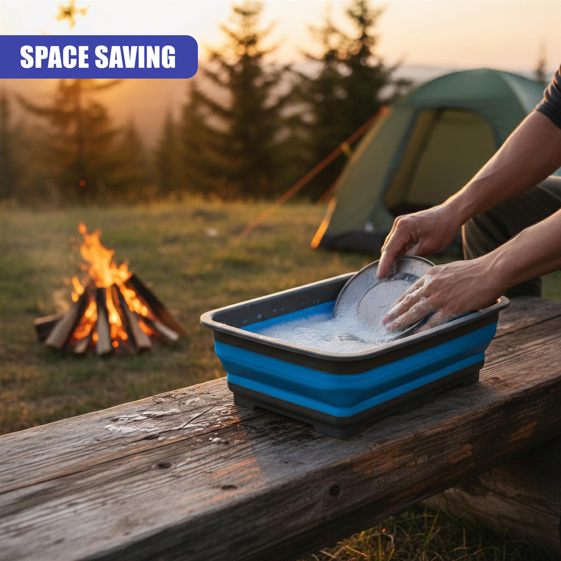 A folding washing up bowl is being used by hands outdoors on a wooden table next to a campfire.
