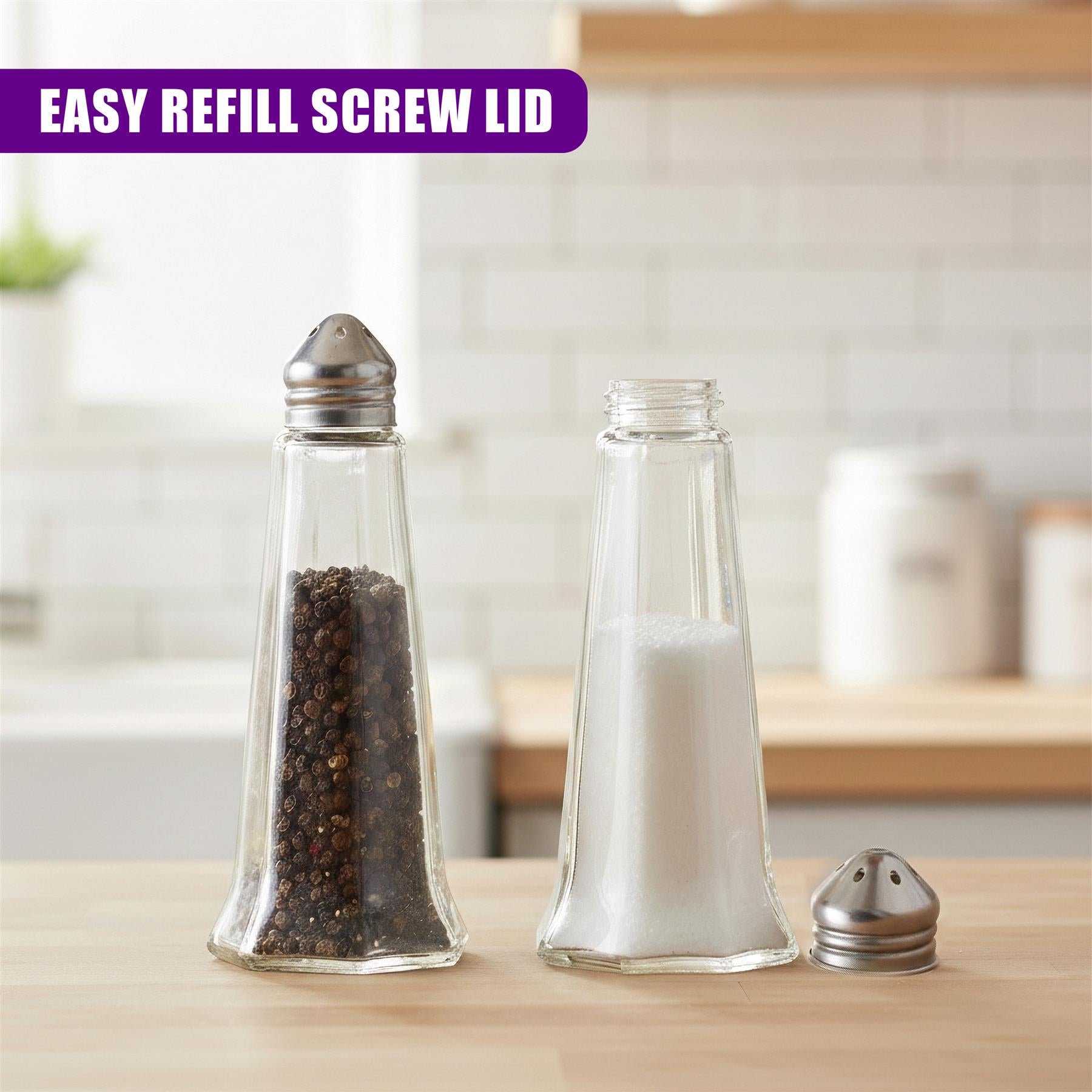 Two clear glass shakers filled with seasonings and a small metal shaker rest on a wooden countertop.