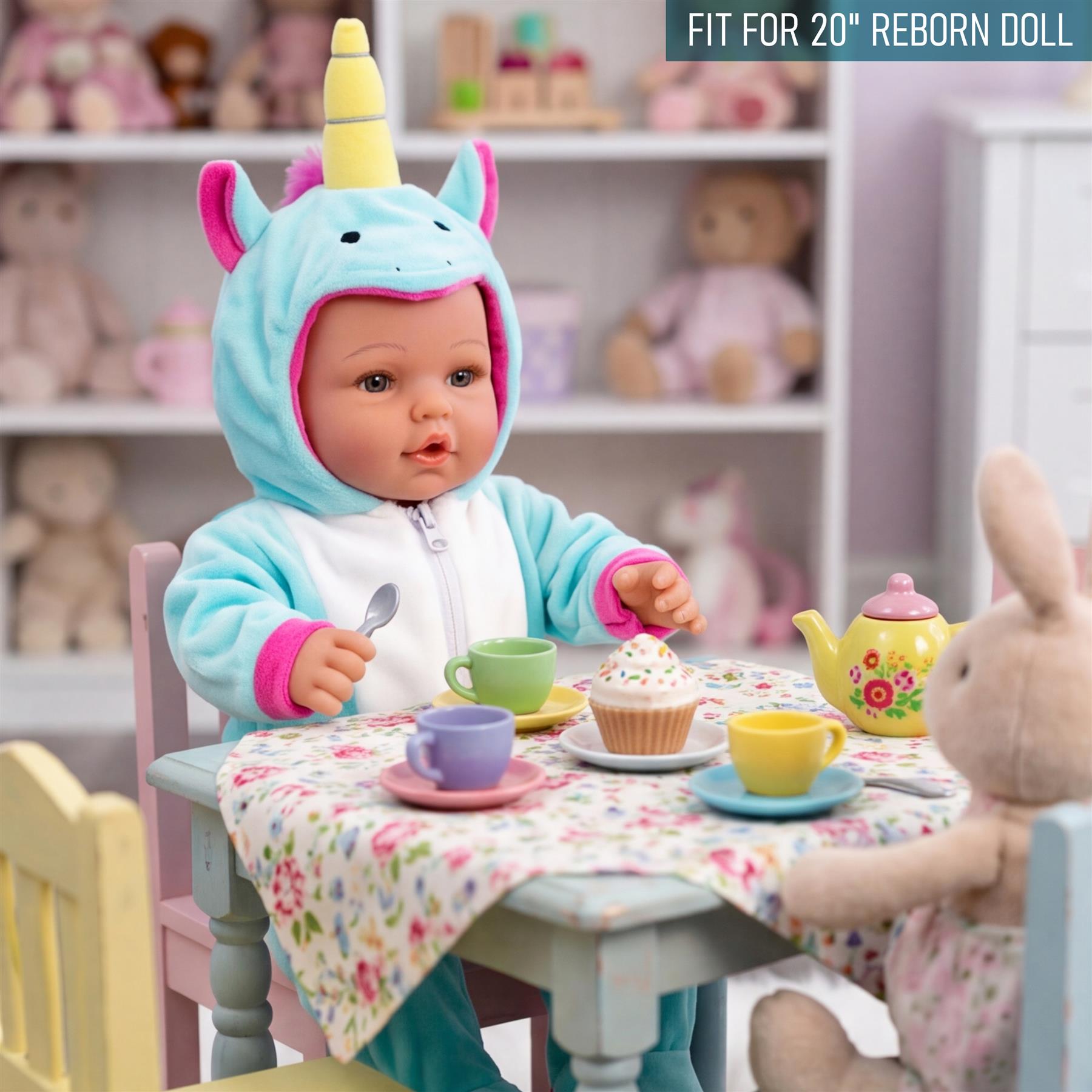 A doll wearing a light blue unicorn costume sits at a table with teacups and pastries.