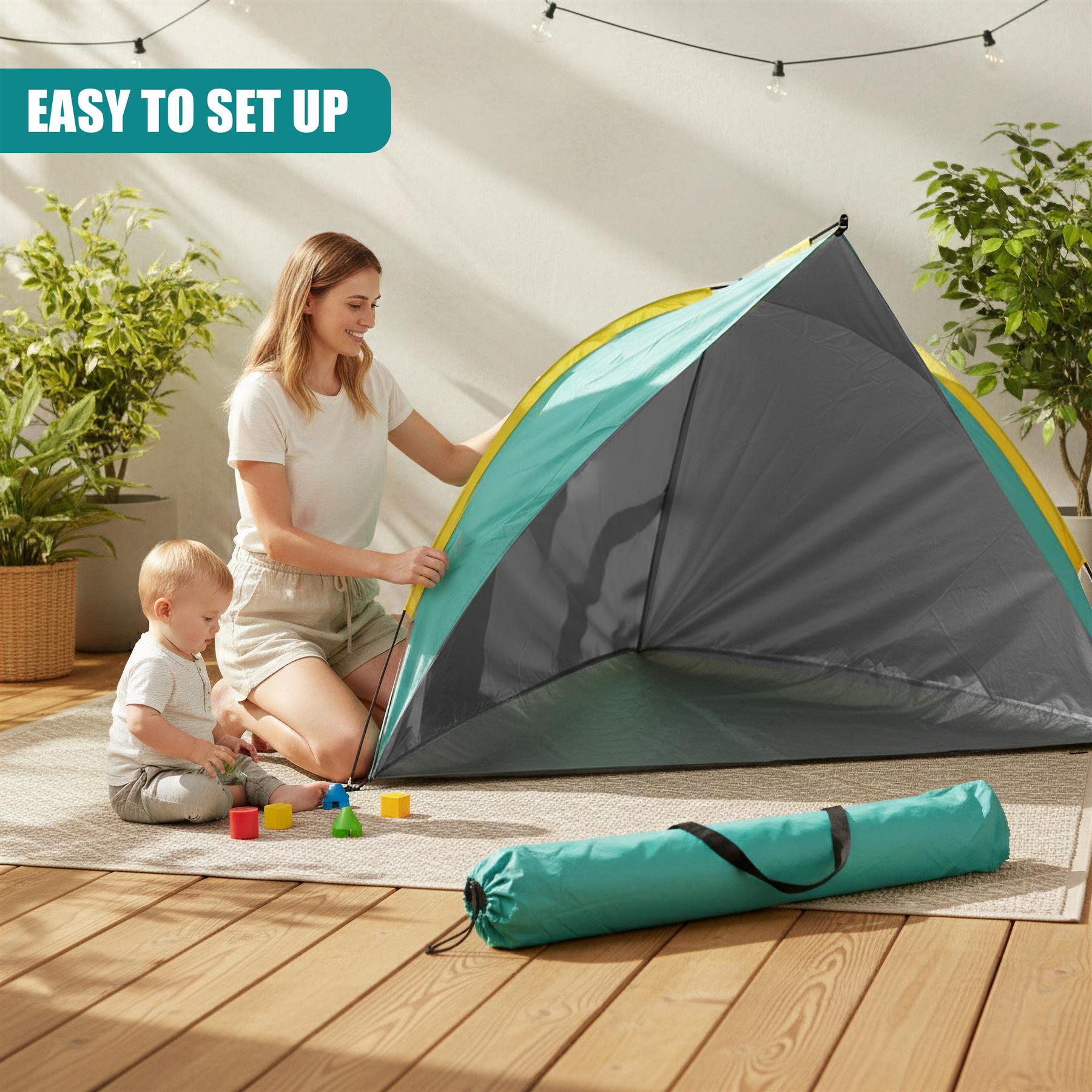 A woman and child near an opened gray and teal beach tent on a wooden floor.