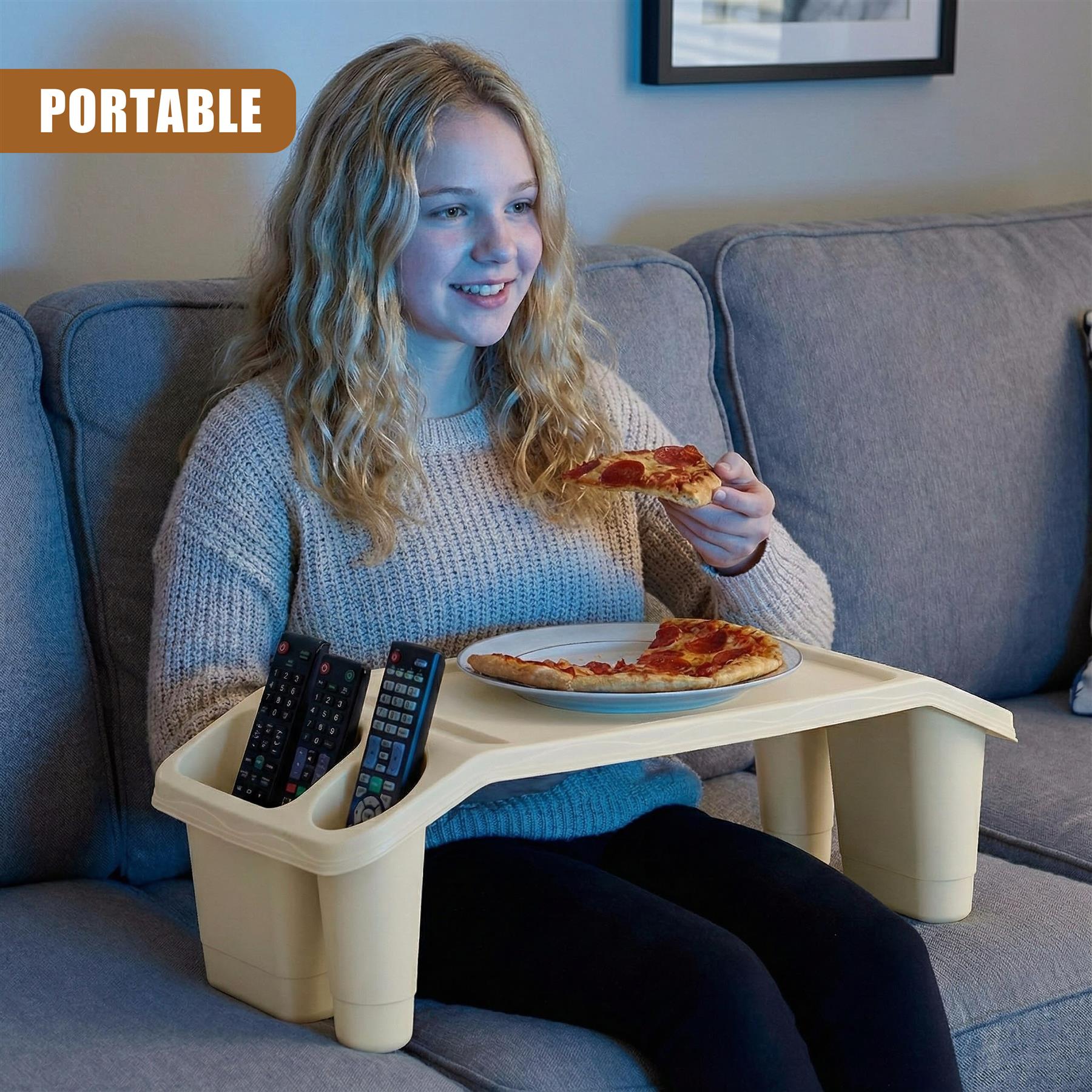A woman sits on a couch, holding a slice of pizza and smiling at the camera. She is using a portable tray with a plate of pizza and a TV remote control. The tray has a small compartment for the remote, and a cup holder on the side. The woman is wearing a beige sweater and has long, wavy blonde hair. The background is a living room with a couch, a TV, and a few other pieces of furniture. The woman is enjoying her pizza and TV. - The Magic Toy Shop