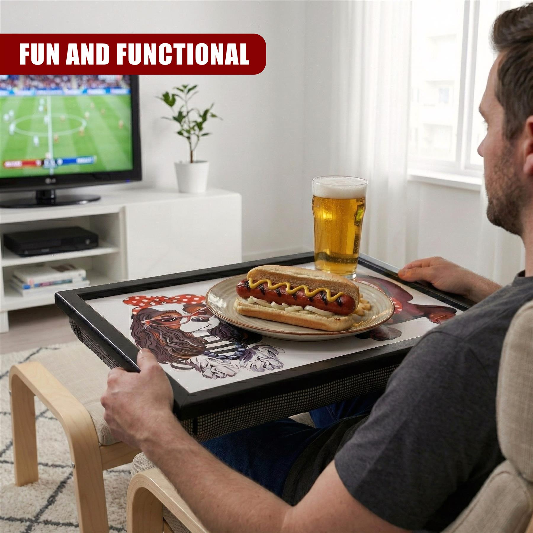Man uses a lap tray holding a plate of hot dogs and a glass of beer in an armchair.