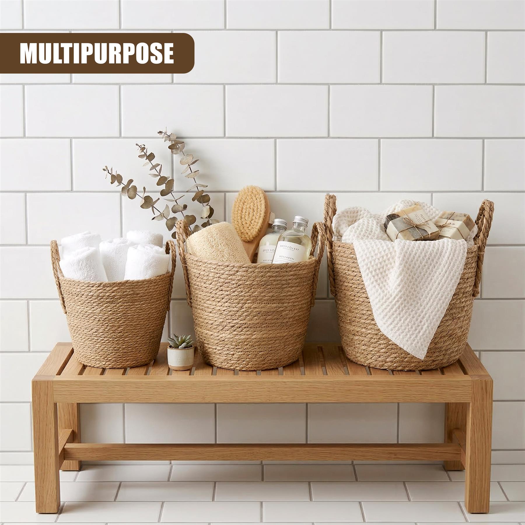 Three woven baskets holding linens, soaps, and miscellaneous items displayed on a wooden bench.