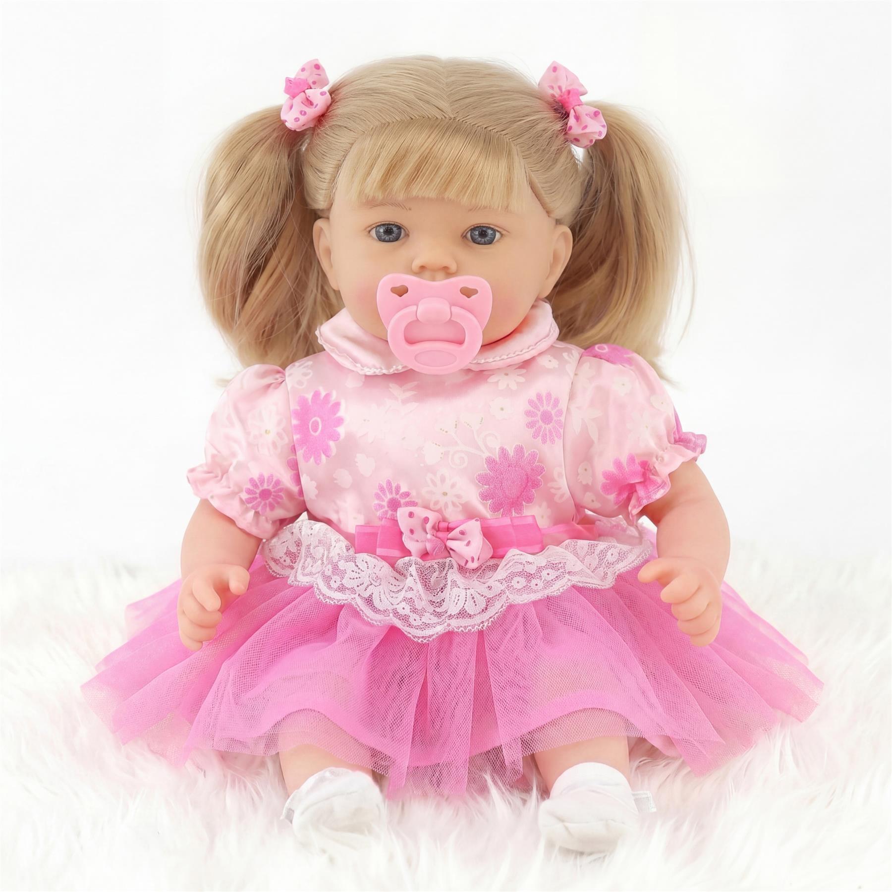 Blonde doll with pigtails wearing a patterned pink top, white lace, and a tulle skirt.