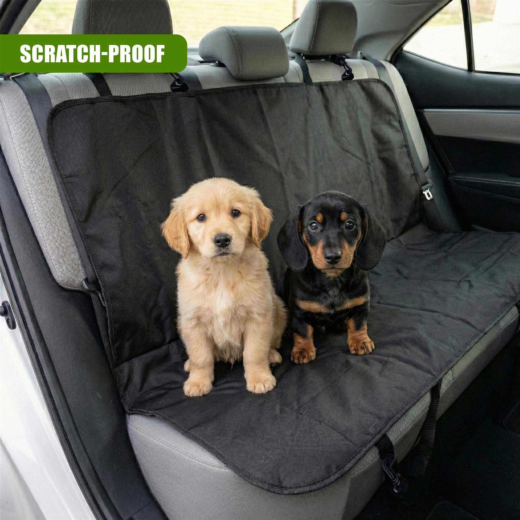 A golden puppy and a black dog are sitting on a protective gray car seat cover inside the vehicle.