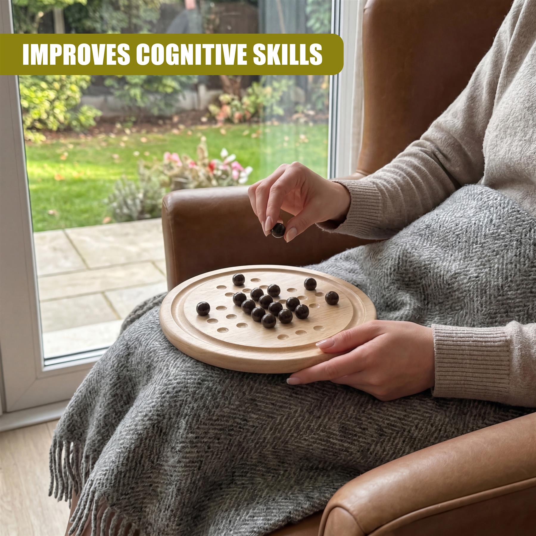 Hands interact with black game pieces on a round wooden solitaire board.