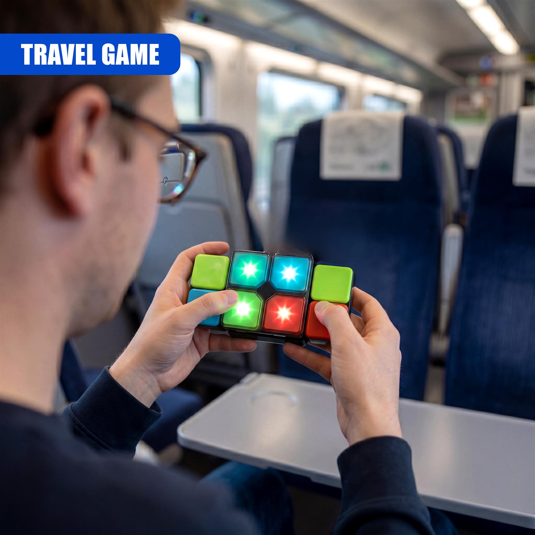Hands manipulate a brightly colored, handheld cube puzzle game while seated inside a train car.