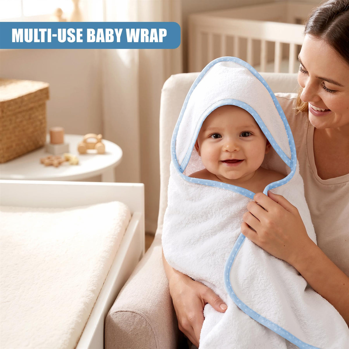A smiling baby is wrapped in a white hooded towel with a blue trim, held by a smiling mother