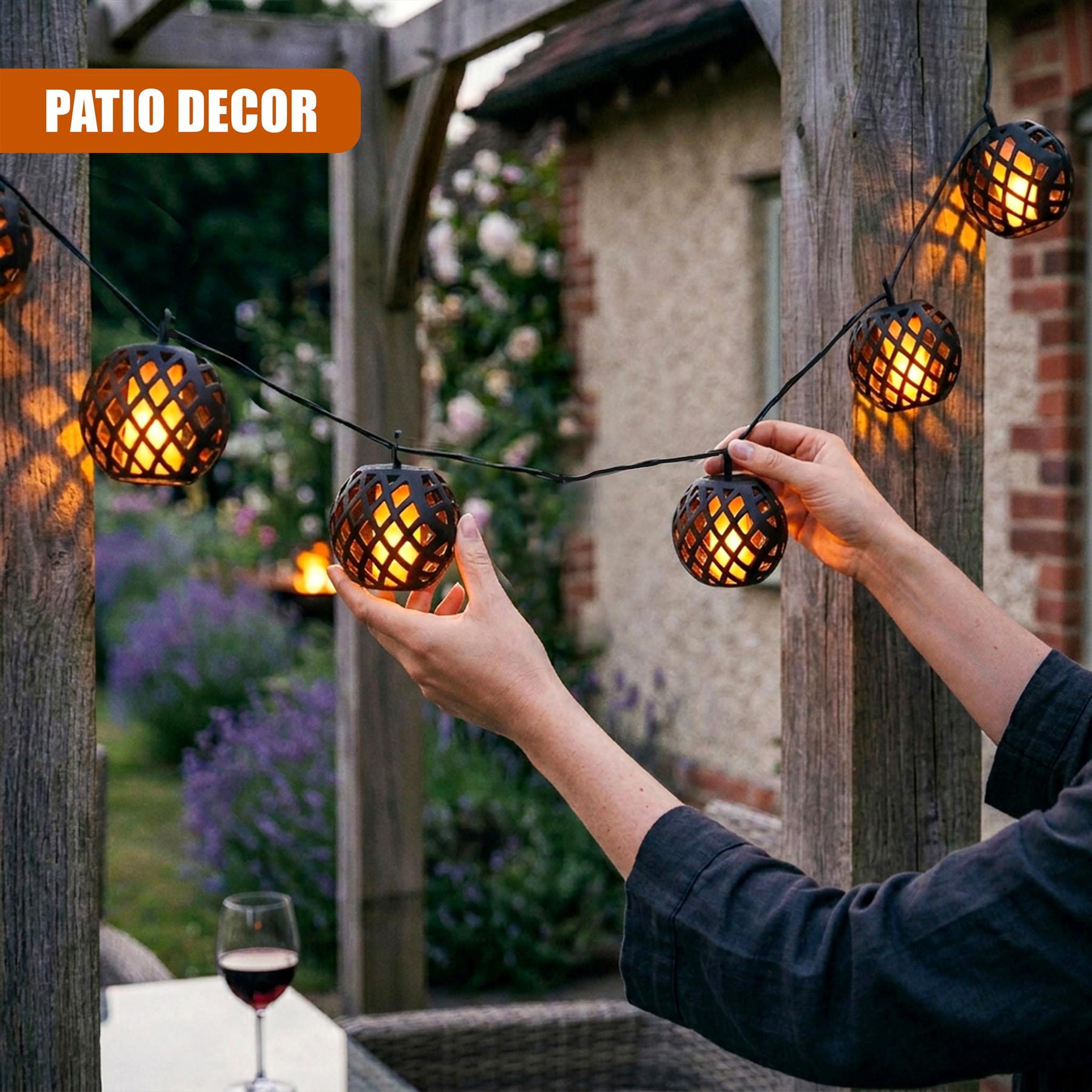 A person adjusts solar string lights featuring woven rattan globe lanterns suspended across a wooden patio.