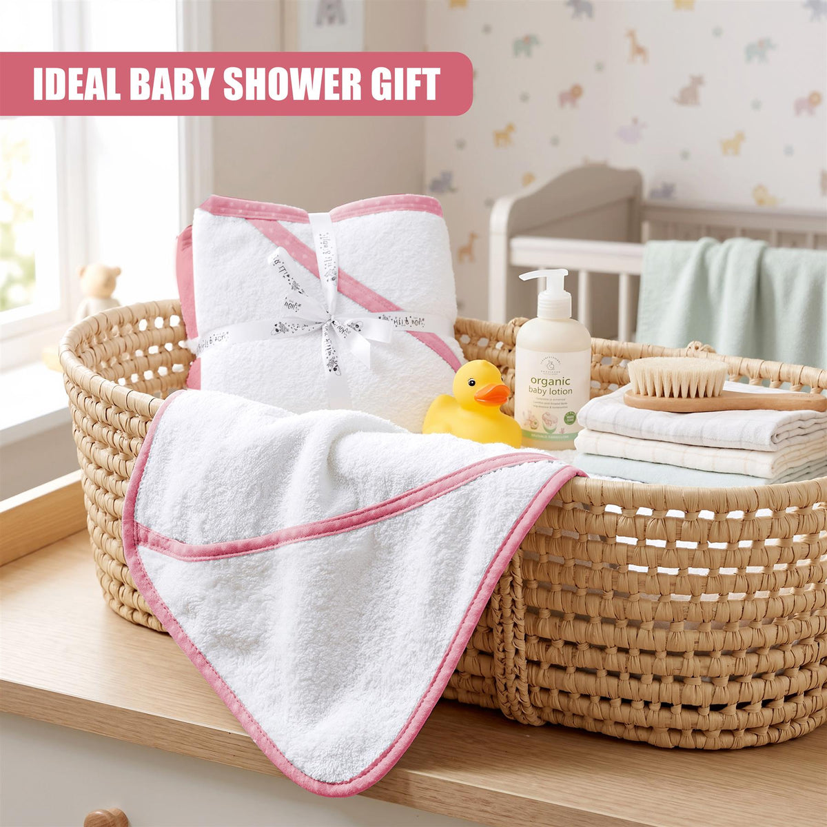 A woven basket contains a set of two pink and white GEEZY hooded baby bath towels with a rubber duck
