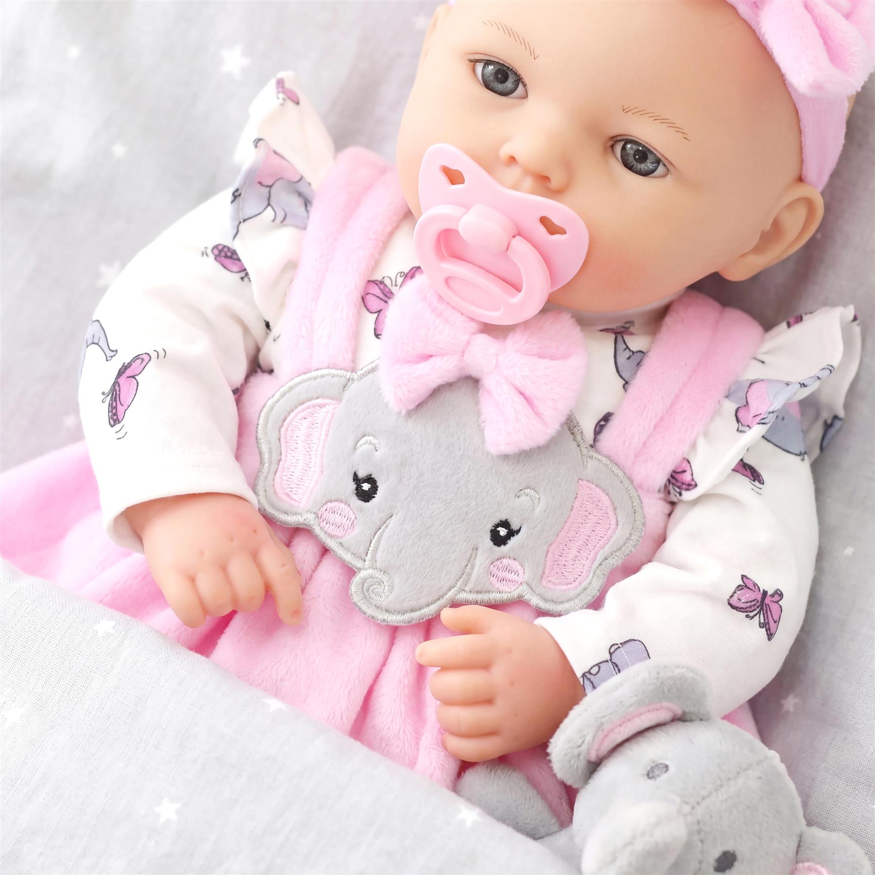 Large doll in white butterfly pajamas and pink outfit, featuring a gray elephant applique and stuffed toy.