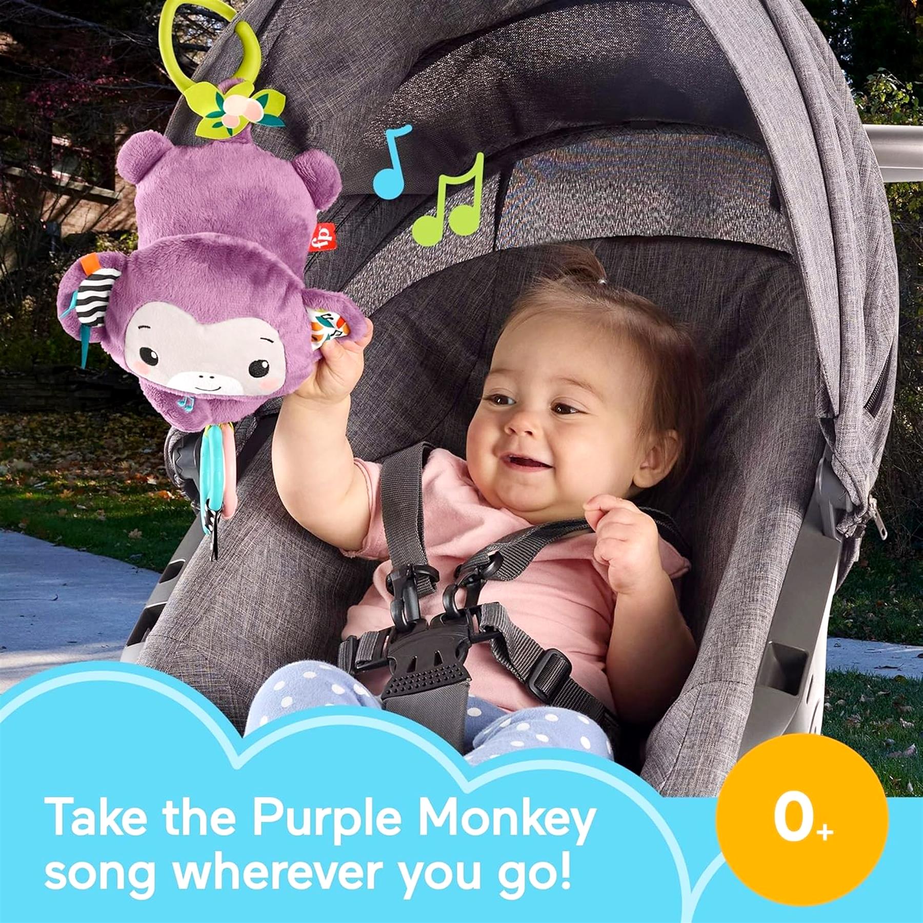 A baby sits in a gray stroller next to a plush purple monkey toy with attached musical notes.
