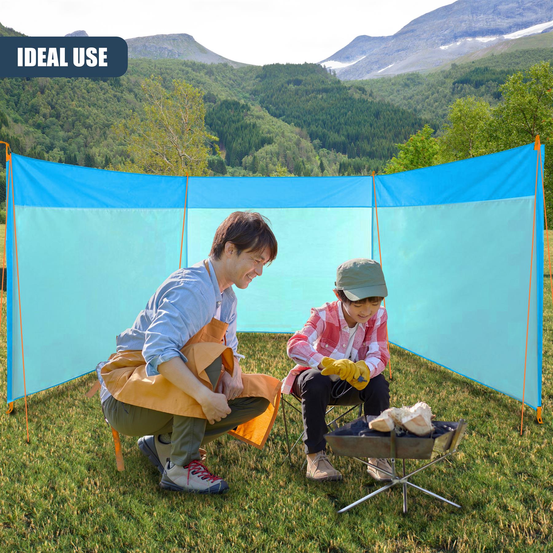 An adult and child sit beneath a blue canopy with camping accessories in a mountainous setting.