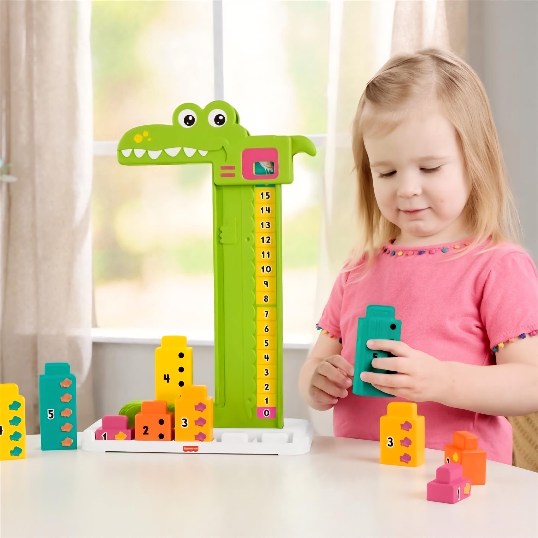 Girl interacts with an alligator toy, number column, and stackable colorful math counting blocks on the table.