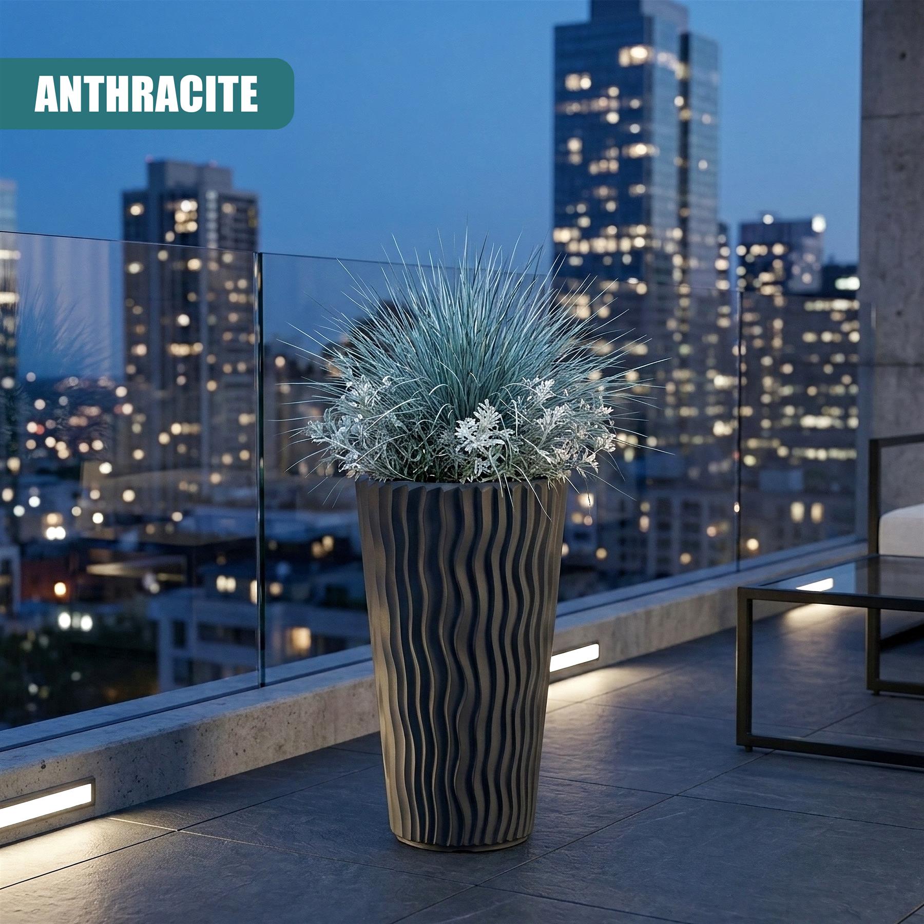 Tall striped anthracite flower pot containing bluish-green ornamental grass on an outdoor patio.