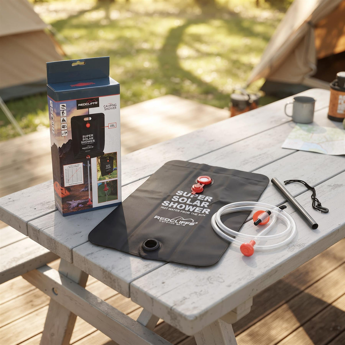 GEEZY Solar Shower Bag, a black PVC container with accessories, sits on a wooden table
