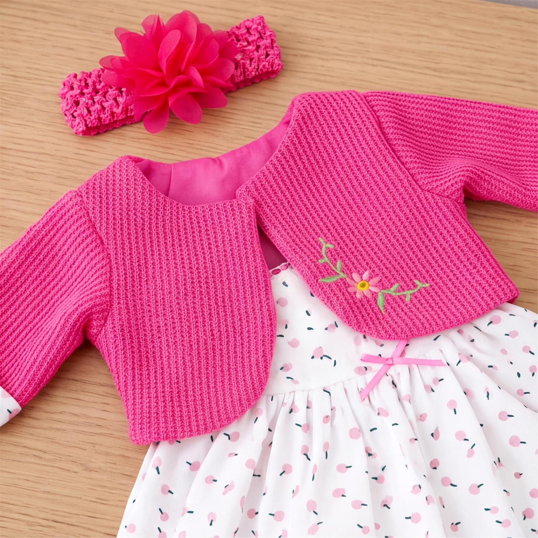 Pink knit cardigans, a floral embroidered top, and a polka dot skirt section for a doll are shown.