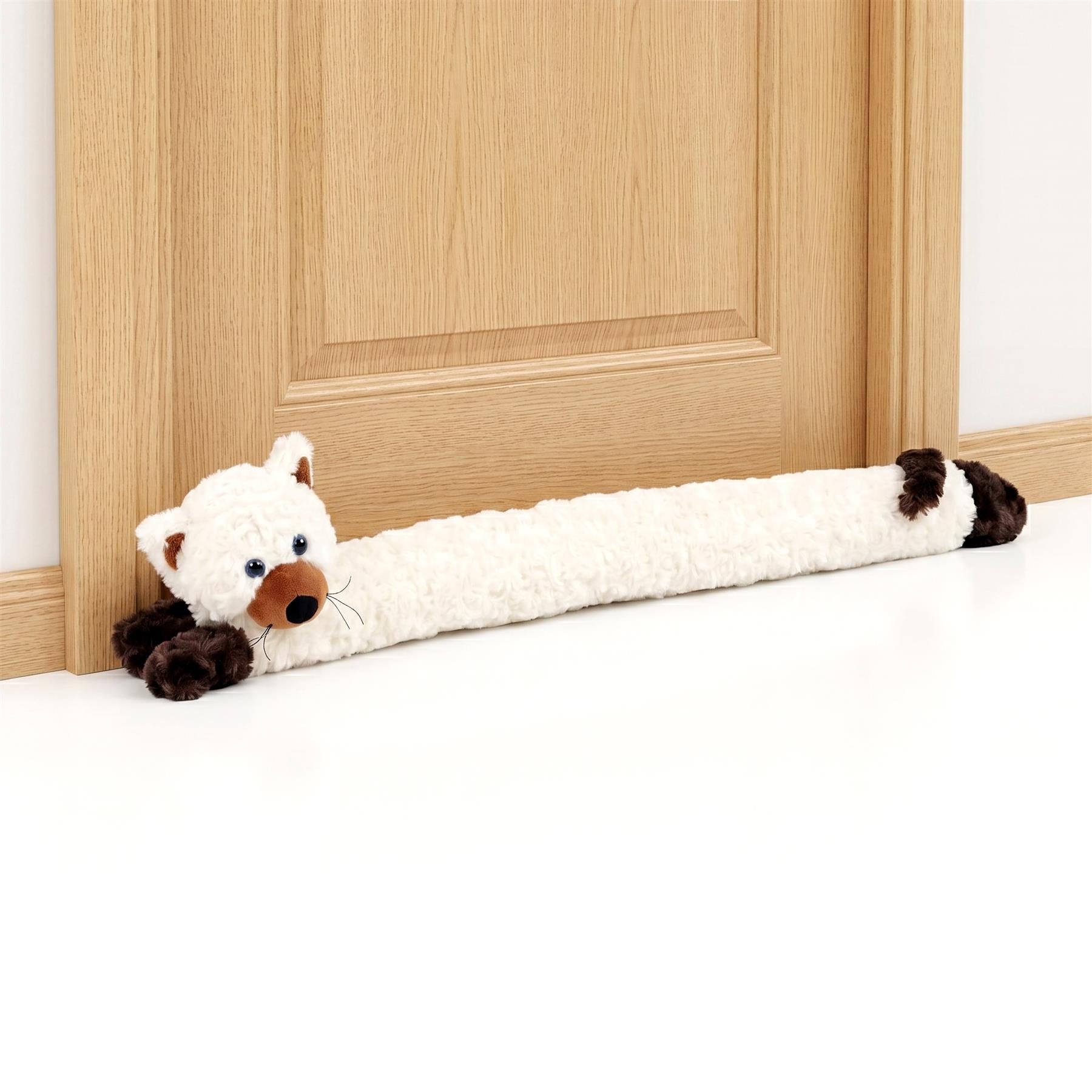 Cream colored plush novelty cat draught excluder resting on the floor against a wooden door.