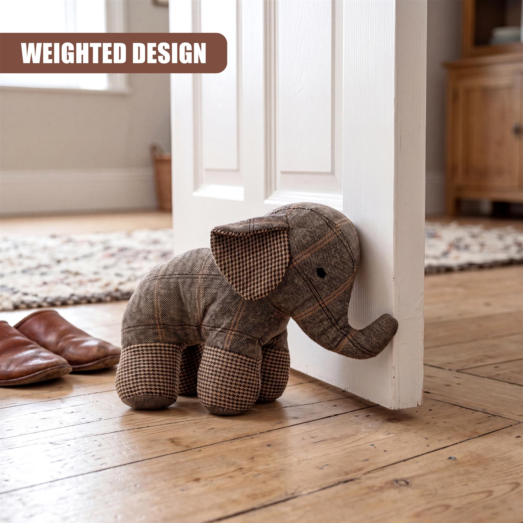 Tartan plaid stuffed elephant door stopper resting against the white painted door edge on a wooden floor.