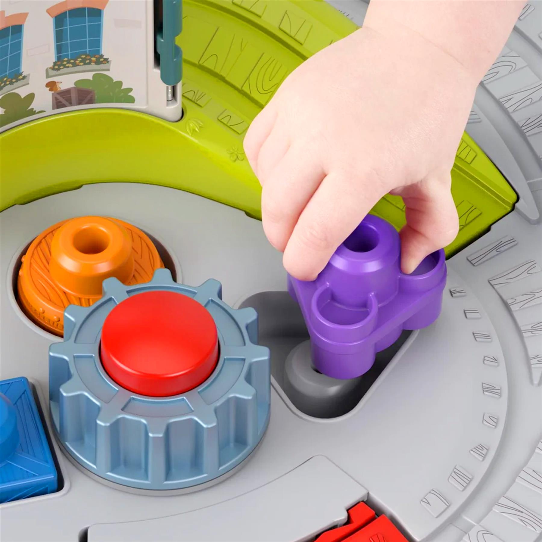 A hand pushes a purple plastic piece onto a rotating toy train track.