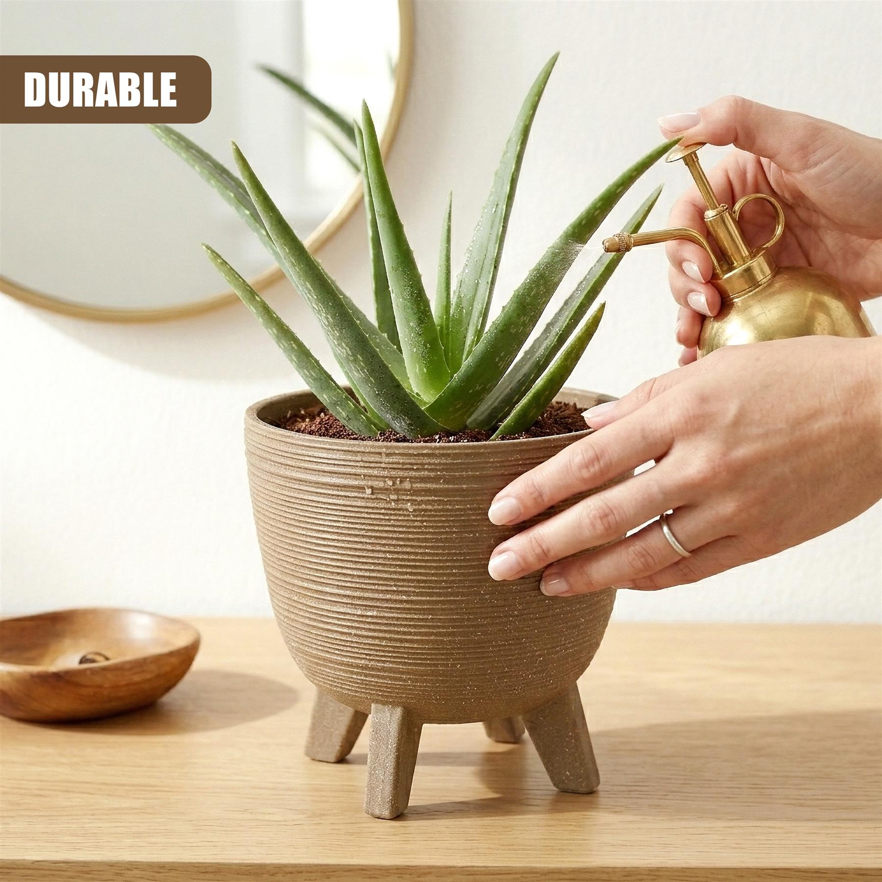 Brown ceramic pot with legs holds a succulent plant receiving water from a brass spout.