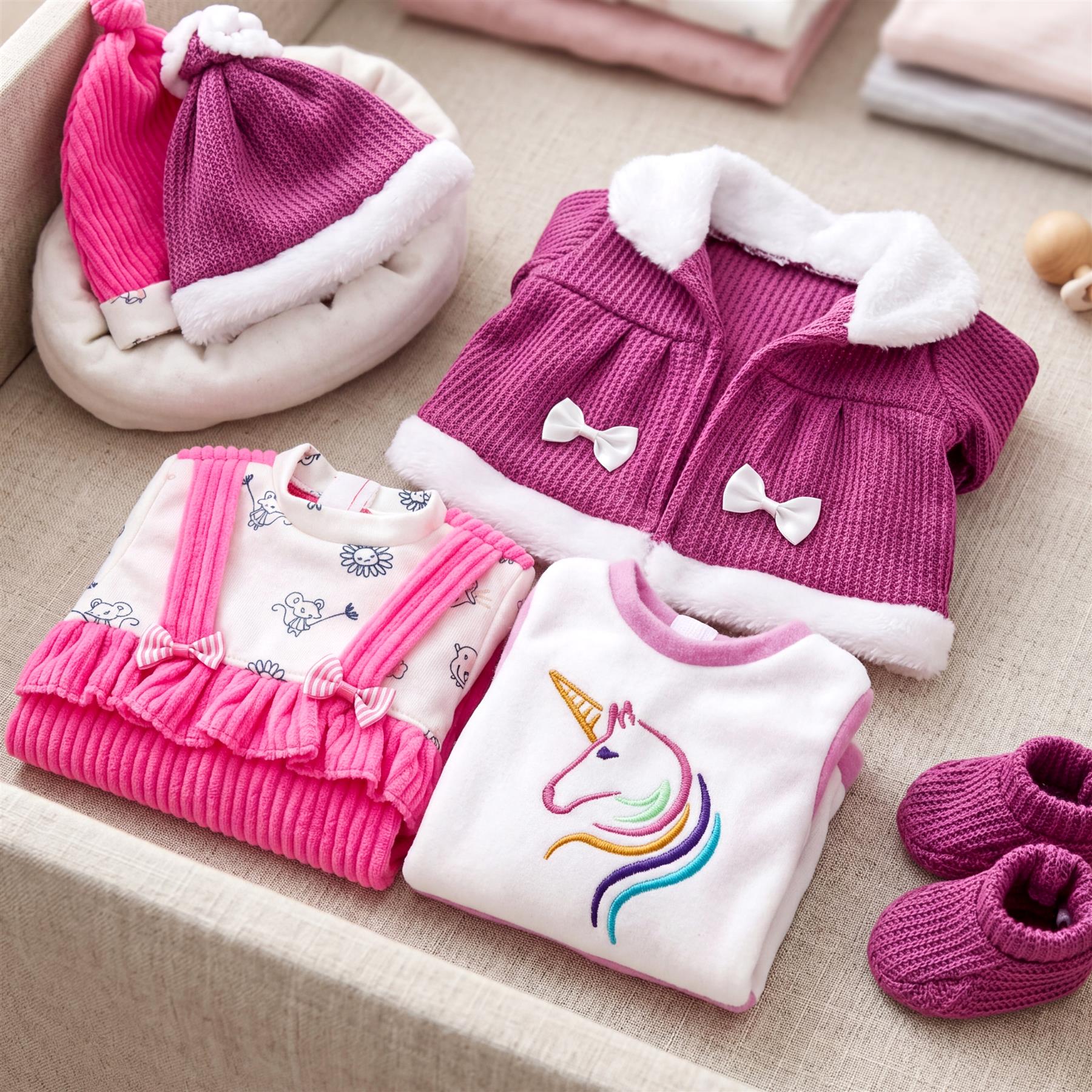 Pink and purple miniature doll outfits including a unicorn top, cozy jacket, and matching booties.