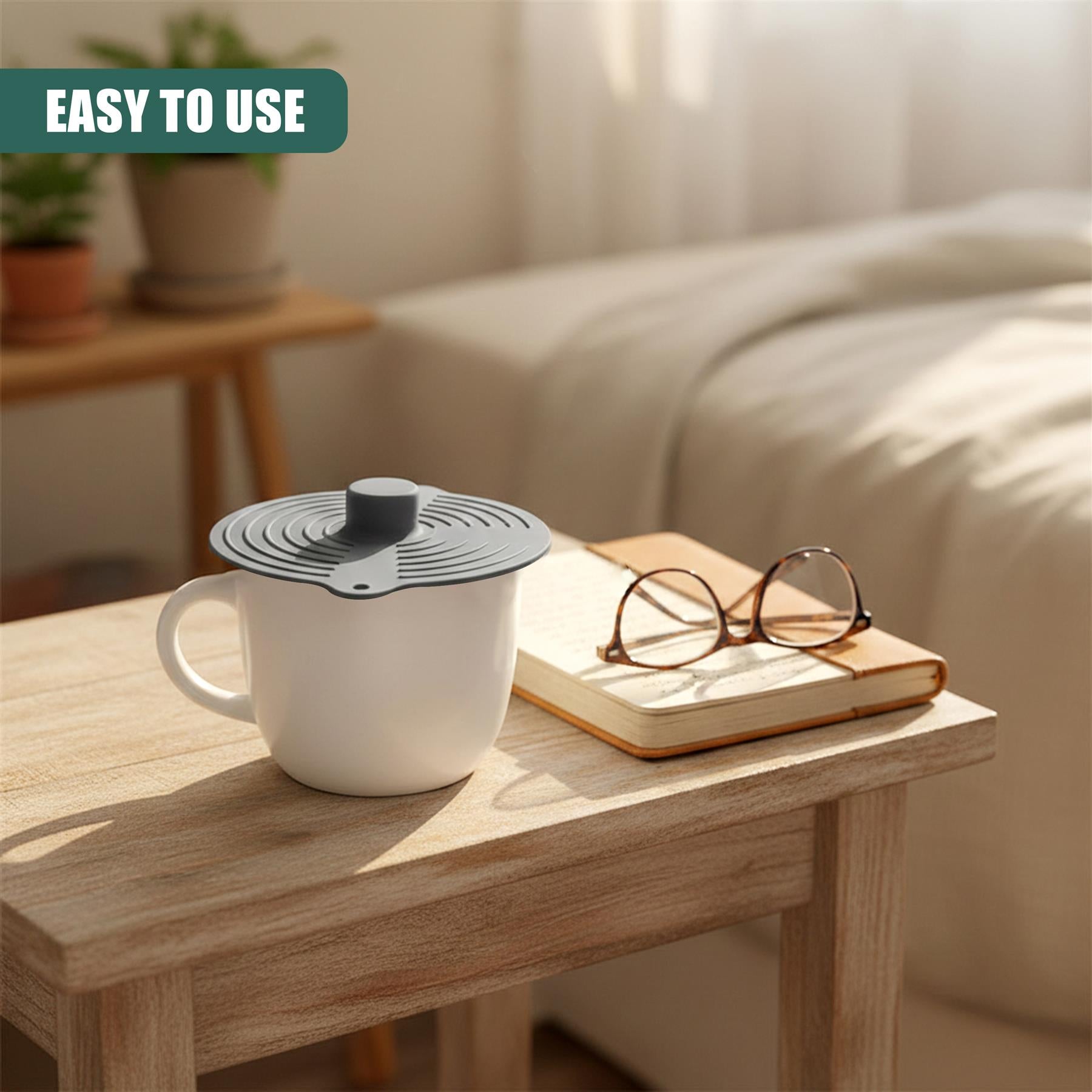 A silicone food cover rests on a white mug, placed on a light wood table surface.