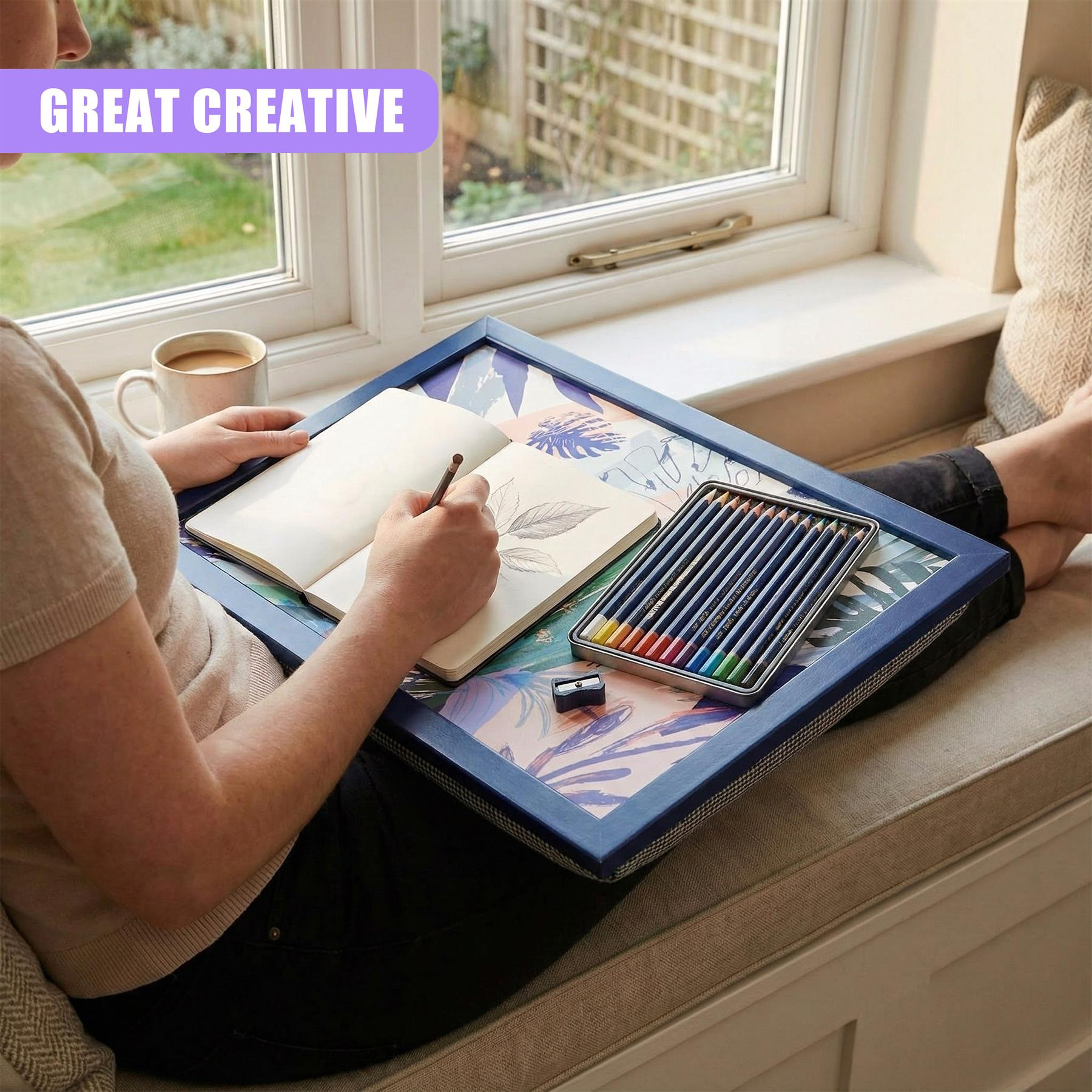 Colorful colored pencils and a notepad rest on a blue, leaf-patterned lap tray.
