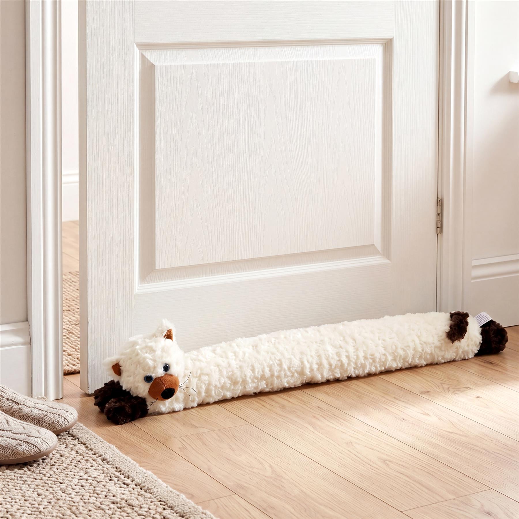 White and black cream cat novelty draught excluder resting on a hardwood floor.
