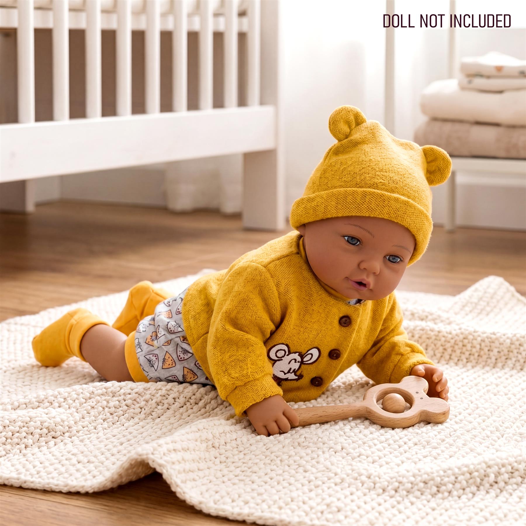 Mustard yellow knitted baby set with a hat, sweater, and patterned bottoms resting on a cream blanket.