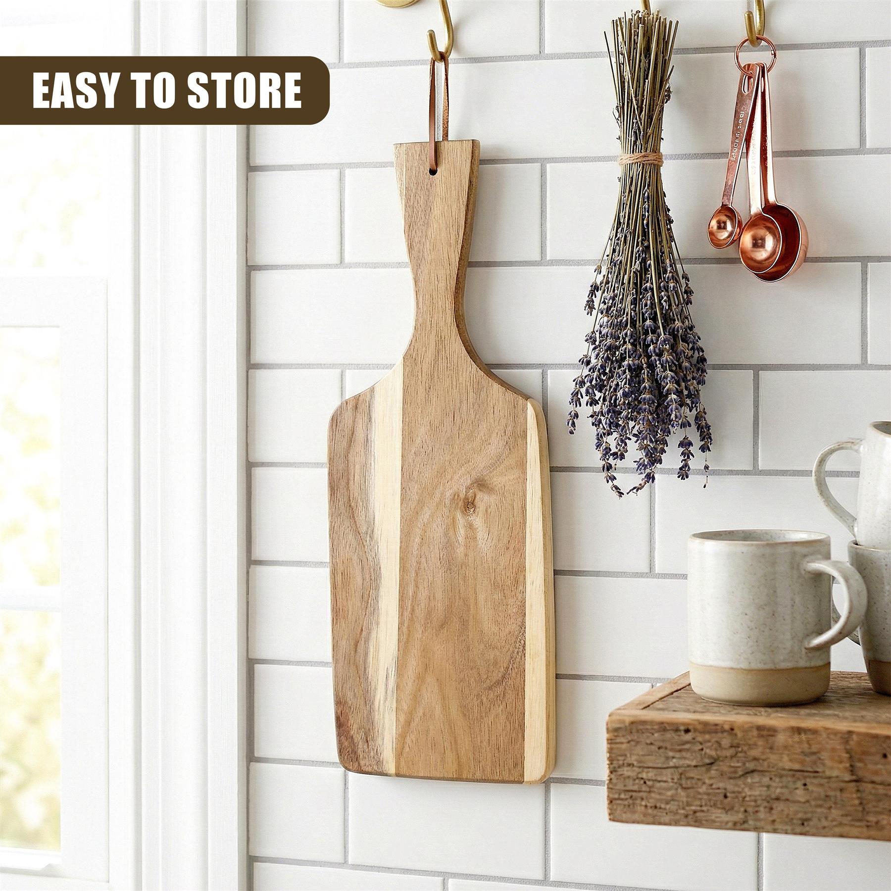 Large wooden paddle board hangs on a white tiled backsplash with copper tools and mugs.