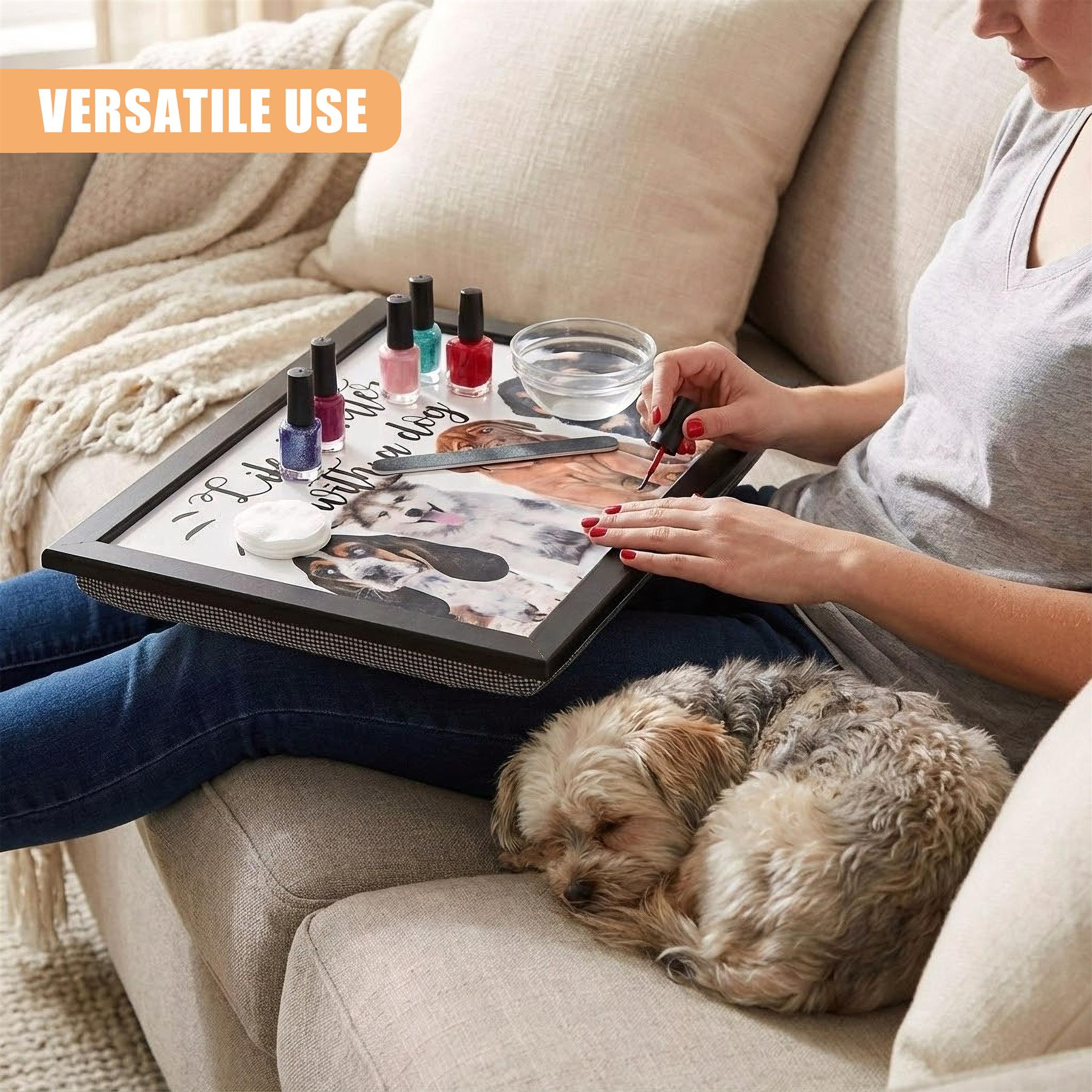 A woman is sitting on a couch with a tray on her lap. The tray contains nail polish, a bowl of water, and a nail file. She is painting her nails with red polish. A small dog is lying next to her on the couch. The woman is wearing a grey t-shirt and blue jeans. The couch is beige. The room has a neutral color scheme. - The Magic Toy Shop
