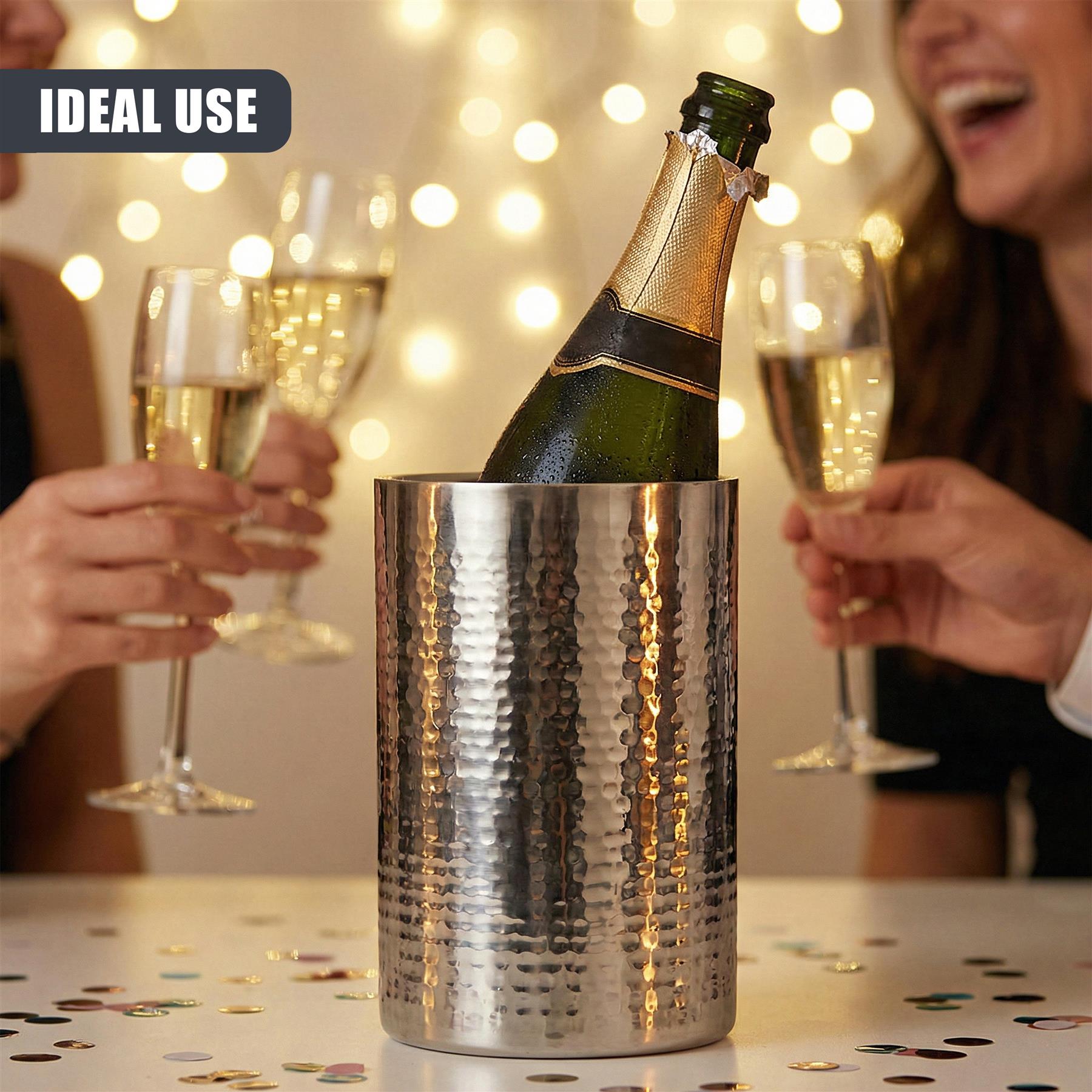 Metallic stainless steel wine cooler holding a dark green bottle on a table during a social gathering.