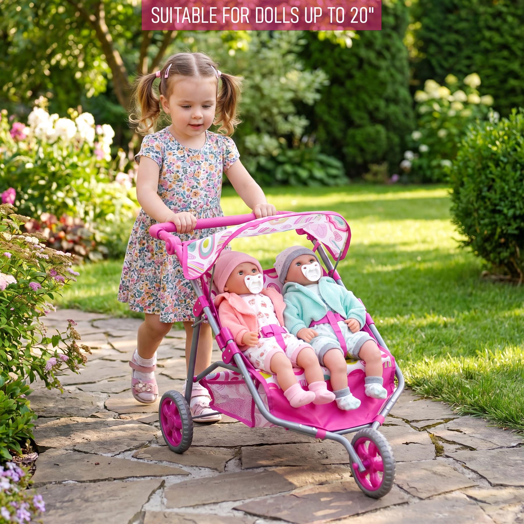 Pink three-wheeled twin doll pushchair with a fabric carrying sling and detachable canopy.