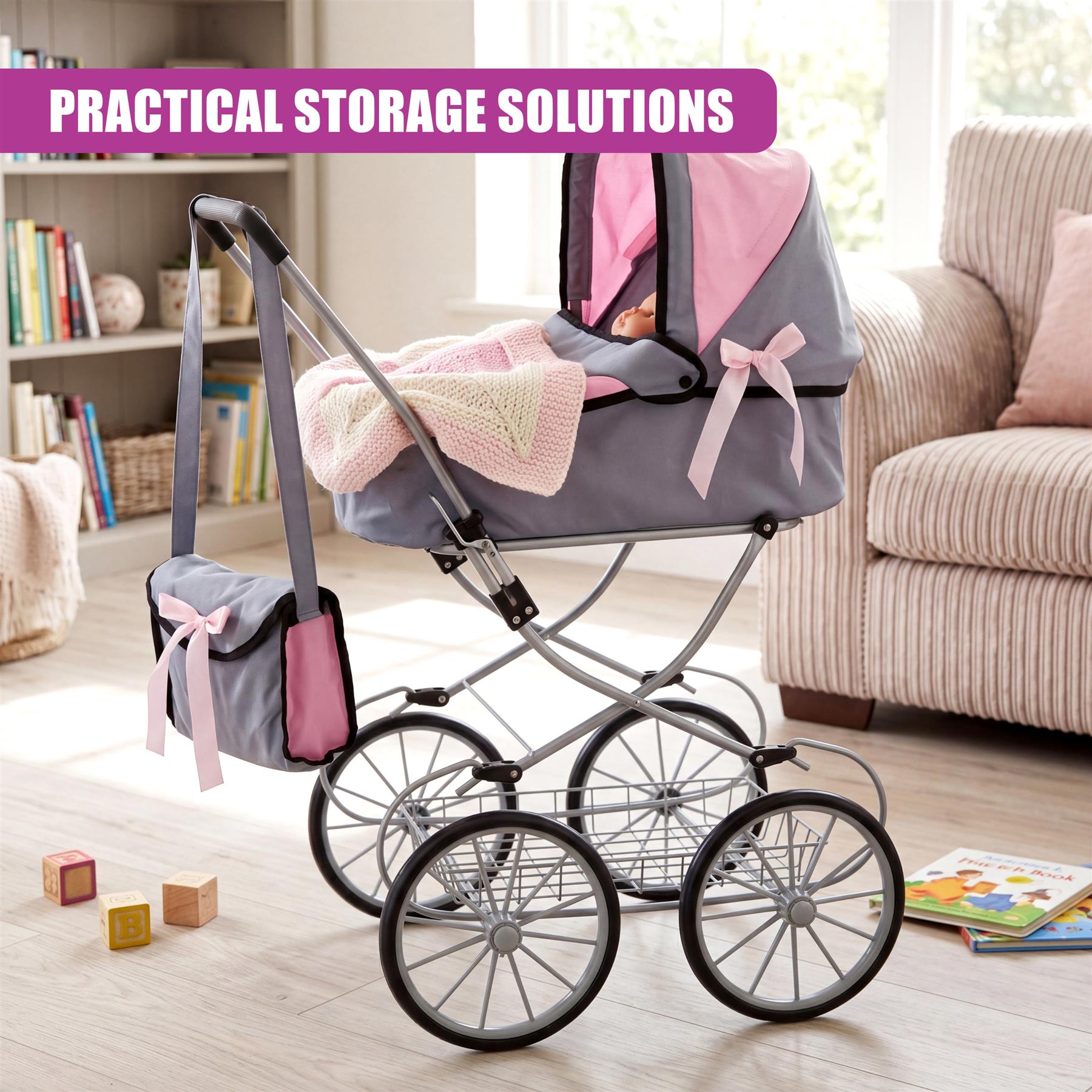 Grey doll pram stroller features large wheels, a fabric carriage, and attached pink storage bags.